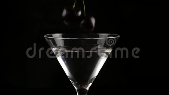 樱桃被扔进一个杯子里酒精鸡尾酒在黑暗的背景下准备鸡尾酒和派对概念慢慢慢慢视频的预览图