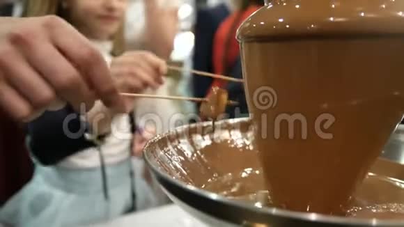 供应活动巧克力喷泉人们使用巧克力喷泉和水果棒视频的预览图