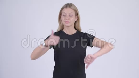 年轻迷茫的金发女郎在竖起大拇指和大拇指之间做出选择视频的预览图