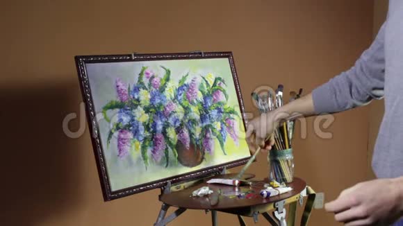 一位穿红色毛衣的长胡子男艺术家画了一支艺术画笔在画室里画着依然存在的花朵视频的预览图