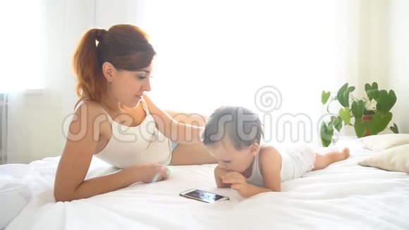 妈妈和宝宝在卧室里看智能手机视频的预览图