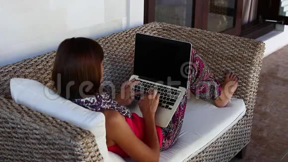 在家享受时光年轻女子坐在别墅外的一辆舒适的马车里在笔记本电脑上工作视频的预览图