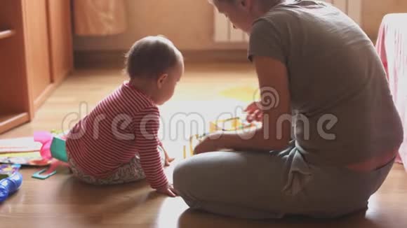 母亲和孩子坐在地板上的房间里玩耍视频的预览图