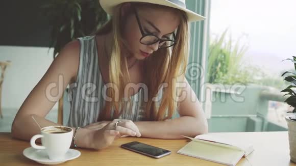 美丽的年轻女性使用手机进行教育女人在咖啡馆里用智能手机视频的预览图