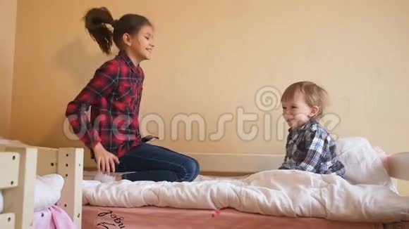 带着蹒跚学步的男孩在床上欢笑和跳跃的少女视频的预览图