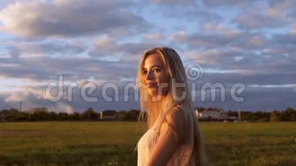 日落时分美丽的女孩在田野里散步视频的预览图