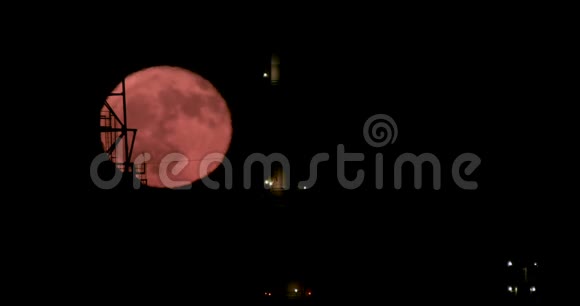 一轮红色满月从大型炼油厂后面升起视频的预览图