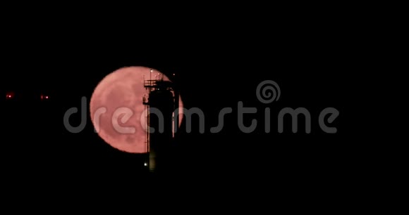 一轮红色满月从大型炼油厂后面升起视频的预览图