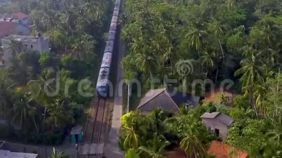 空中拍摄的老火车乘坐棕榈树和别墅穿越热带视频的预览图