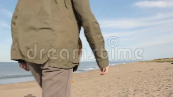一个留着胡子的中年男人穿着灰色的裤子穿着绿色的夹克和黄色的靴子转过身来看着视频的预览图