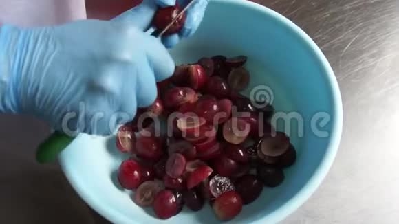 在食品工业中用刀子把黑葡萄切在碗里视频的预览图