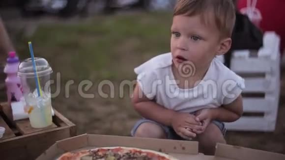 年轻漂亮的女人和小男孩在夏天在公园休息男孩吃披萨然后指着他妈妈视频的预览图