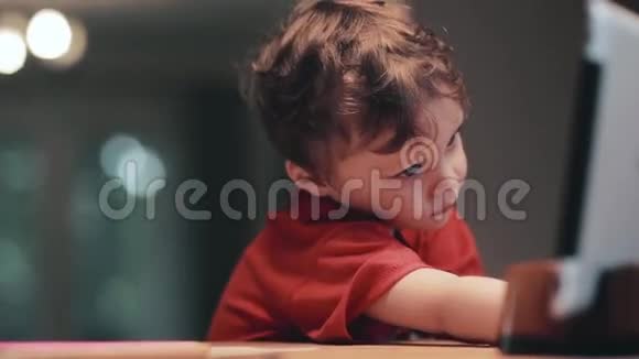 可爱的小男孩玩平板电脑用手指触摸显示器微笑视频的预览图