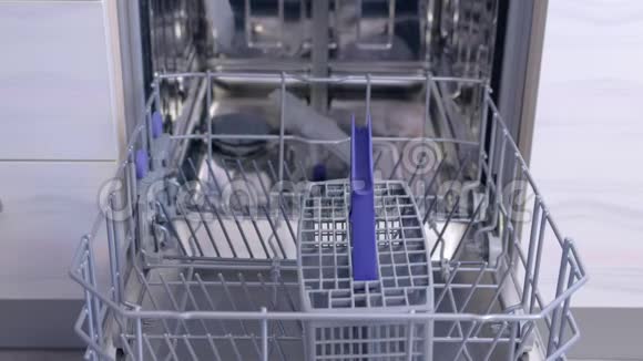 男人洗碗装洗碗机放餐具和厨具篮视频的预览图