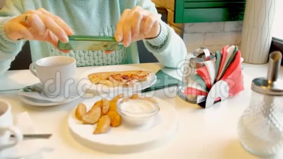 女士使用智能手机在餐厅拍照近距离拍摄食物视频的预览图