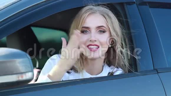夏天美丽的金发女孩在汽车的窗户上挥舞着亲吻视频的预览图