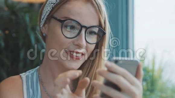 女孩在智能手机上给男朋友写信微笑着在咖啡馆用手机的女人视频的预览图