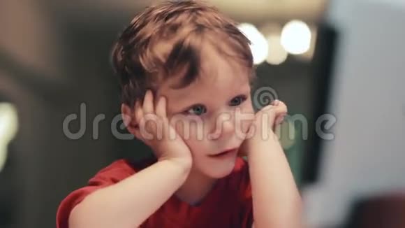 疲惫可爱的小男孩穿着红色衬衫双手靠近脸摸着脸颊有一张滑稽的脸视频的预览图