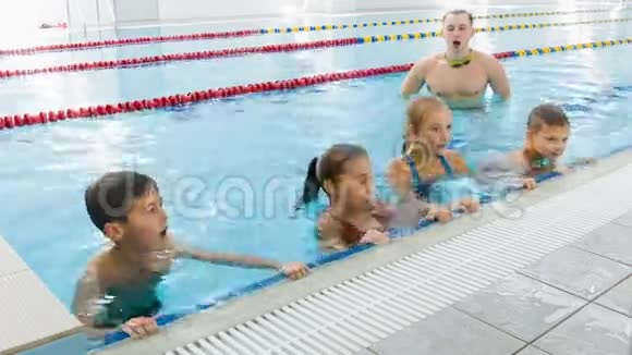 教练或教练和一群孩子在游泳池里做运动视频的预览图