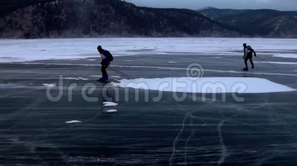 在美丽的日落中两个人正在冰封的贝加尔湖上滑冰视频的预览图
