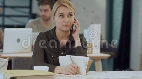 在办公桌前打电话给可爱的年轻女性视频的预览图