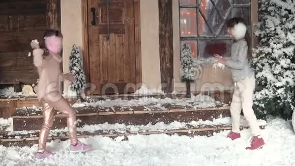 圣诞节或新年孩子们在人造雪中玩得很开心圣诞装饰两个小女孩在门廊上视频的预览图