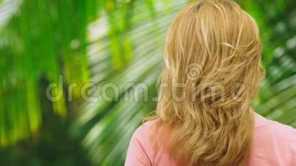 美丽的金发女人在大自然中抚摸她的头发后景头发处理概念视频的预览图