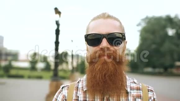 戴墨镜看镜头微笑城市背景的时髦胡子游客画像视频的预览图