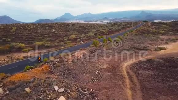 骑自行车的人在沙漠公路上旅行的鸟瞰图视频的预览图