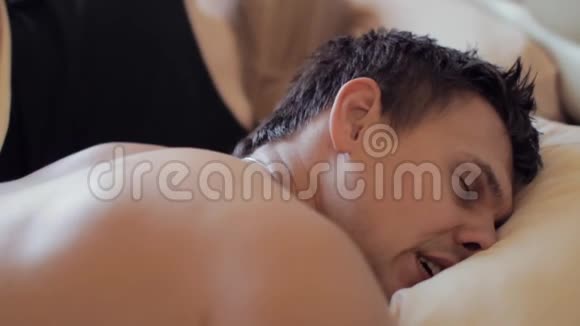 女人醒来在床上和睡着的肌肉发达的丈夫说话清晨视频的预览图