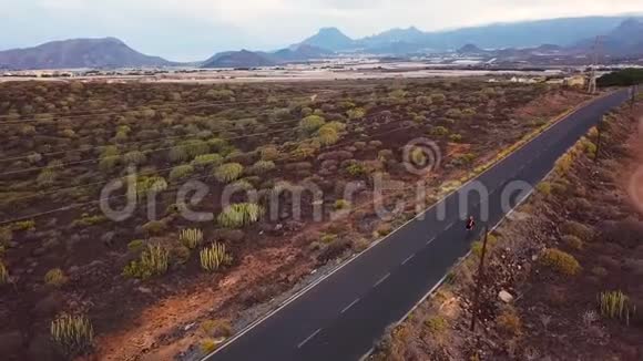 骑自行车的人在沙漠公路上旅行的鸟瞰图视频的预览图