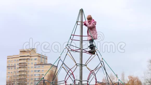 穿暖和衣服的小女孩爬起来挂在操场上视频的预览图