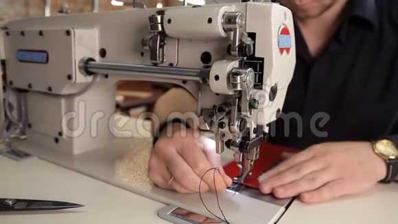 在车间里一个人用缝纫机缝制真皮皮革制品制造程序视频的预览图