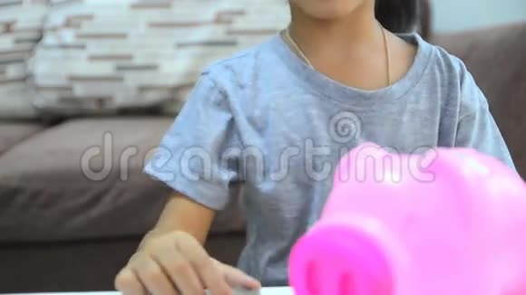 高清特写镜头亚洲小女孩把硬币放进储蓄罐视频的预览图