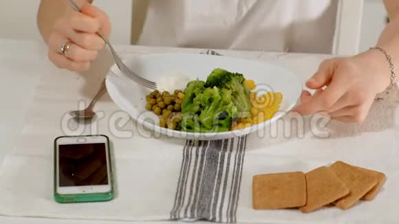 在家里的餐桌上一位美丽的女人很高兴地吃西兰花和青视频的预览图