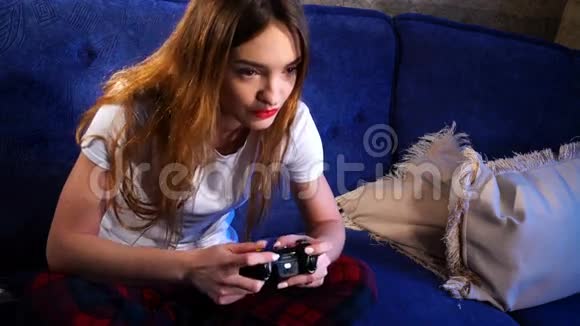穿着白色T恤的女孩坐着玩电脑游戏视频的预览图