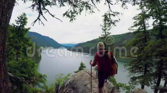成熟的女人站在河边的岩石上视频的预览图