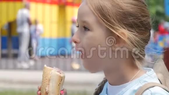漂亮的年轻女孩在公园里吃热狗视频的预览图