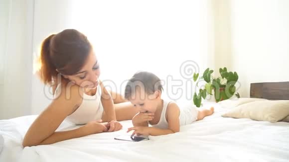 妈妈和宝宝在卧室里看智能手机视频的预览图