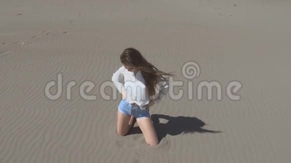 美丽的年轻女子吹着头发摆在镜头前黑发在海滩上享受生活慢动作夏季视频的预览图