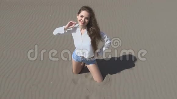美丽的年轻女子吹着头发摆在镜头前黑发在海滩上享受生活慢动作夏季视频的预览图