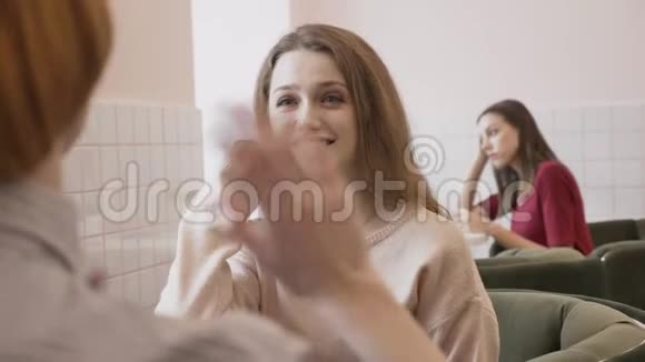 三个白种人女孩坐在咖啡馆里微笑交谈对话八卦的概念背景60fps视频的预览图