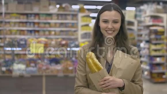 可爱的女孩站在超市手里拿着一个小面包视频的预览图
