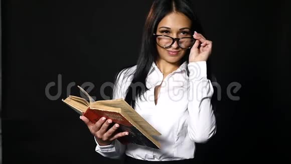 肖像吸引人的女人读书美丽的年轻黑发长发穿着白色衬衫摆在工作室里视频的预览图