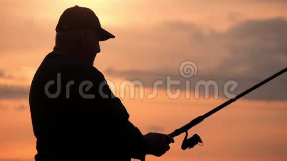 剪影渔夫在背景黄昏日落时在河中投掷鱼竿钓鱼时傍晚美丽的日落视频的预览图