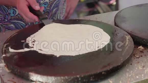 女人的手用特纳水龙头在煎饼机上烤煎饼视频的预览图