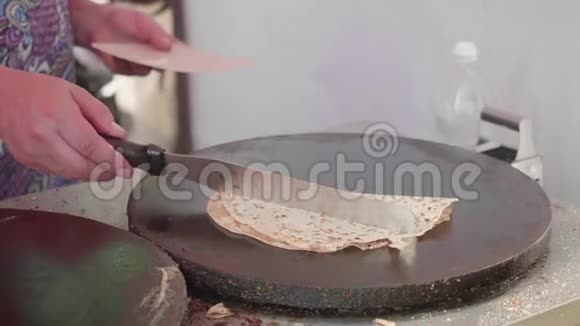 女人用特纳的手在煎饼制造者的另一边烤煎饼视频的预览图