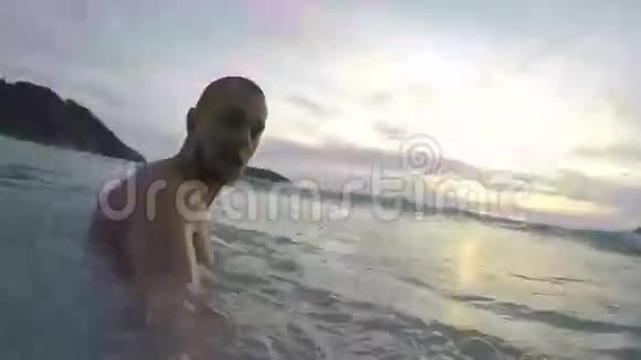 长胡子的年轻运动员走进大海在波浪下潜水戈普罗高清日落自拍泰国普吉岛视频的预览图