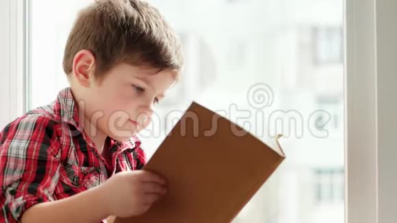 孩子拿着书聪明的男孩翻书页孩子特写肖像孩子读书视频的预览图