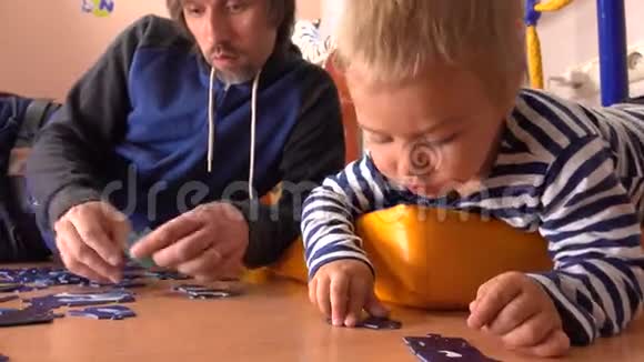 小胡子和他可爱的小儿子一起组装拼图父亲和他的小男孩有空闲时间视频的预览图
